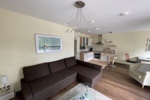 Een moderne woonkamer met een bank, een eettafel en een keuken op de achtergrond.