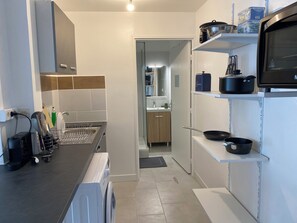 Une cuisine moderne équipée d’un lave-linge, d’un égouttoir et d’un four à micro-ondes posés sur le plan de travail.