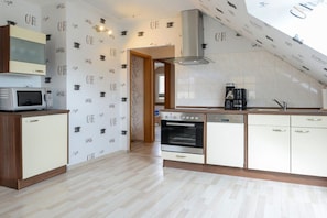 Een keuken met een magnetron, oven, koffiezetapparaat en een spoelbak.