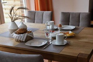 A dining table set with plates, cutlery, a cup, a glass of water, and a basket of bread. - Holiday apartment with 1 bedroom (Borkum)