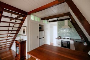 A kitchen with wooden beams, white cabinets, and a wooden countertop. - Deep South: A Joyful A-frame Cabin (Denmark)