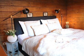 A neatly made bed with pillows and a blanket, two bedside lamps, a small table with a plant, and framed pictures on the wall. - Holiday home with 3 bedrooms (Willingen)