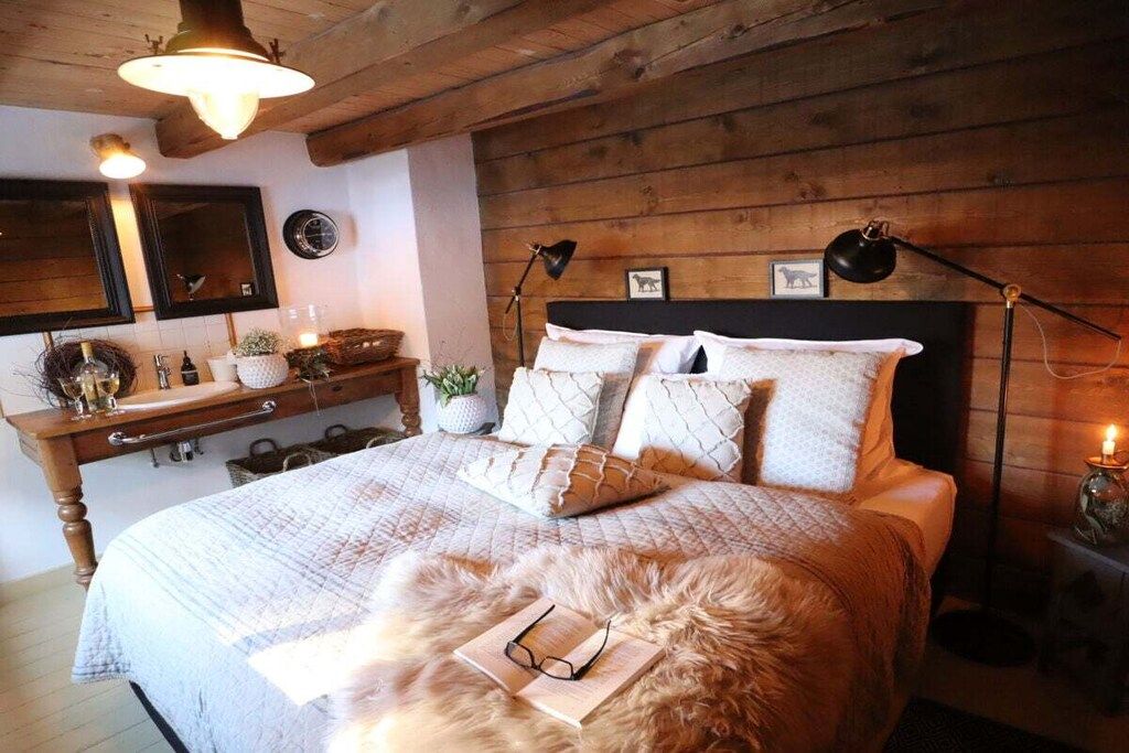Une chambre à coucher avec une tête de lit en bois, une table de chevet avec une lampe et un tapis moelleux.
