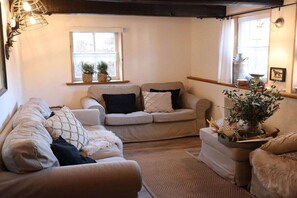 A cozy living room with a sofa, a small table with a plant, and a window with a view. - Holiday home with 3 bedrooms (Willingen)