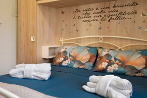 Ein ordentlich bezogenes Bett mit floralen Kissen und gefalteten Handtüchern.