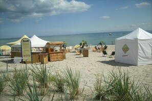 Een strand met tenten, een houten kraampje en strandstoelen.