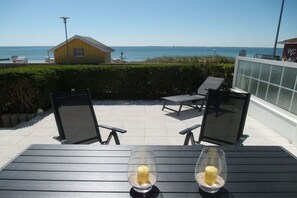 A patio with two tables, chairs, and a view of the ocean. - Holiday apartment with 1 bedroom (Sierksdorf)