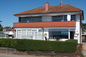Een tweelaags huis met een rood pannendak, een groot raam en het nummer '10' aan de zijkant.