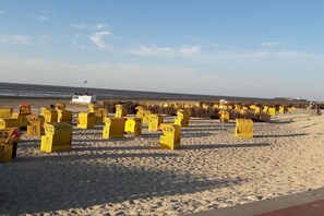 Ein Strand mit gelben, nummerierten Markierungen, einem Boot und einer Flagge.
