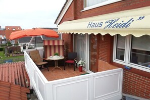 A residential property with a balcony, a dining area, and a window with a curtain. - - Heidi - Apartment Sea Sounds (Borkum)
