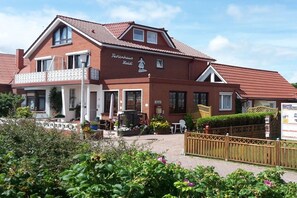 A two-story building with a red-tiled roof, a balcony, and a sign that reads 'Fischerhaus Hotel'. - - Heidi - Apartment Sea Sounds (Borkum)