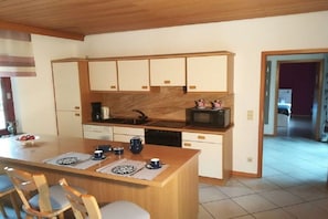A compact kitchen with a central island, built-in appliances, and a dining area with chairs. - Holiday home with 1 bedroom (Hambühren)