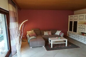 Ein Wohnzimmer mit Ecksofa, Couchtisch und einer Schrankwand.