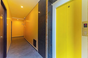 Un pasillo con un ascensor amarillo y una puerta con pantalla digital.