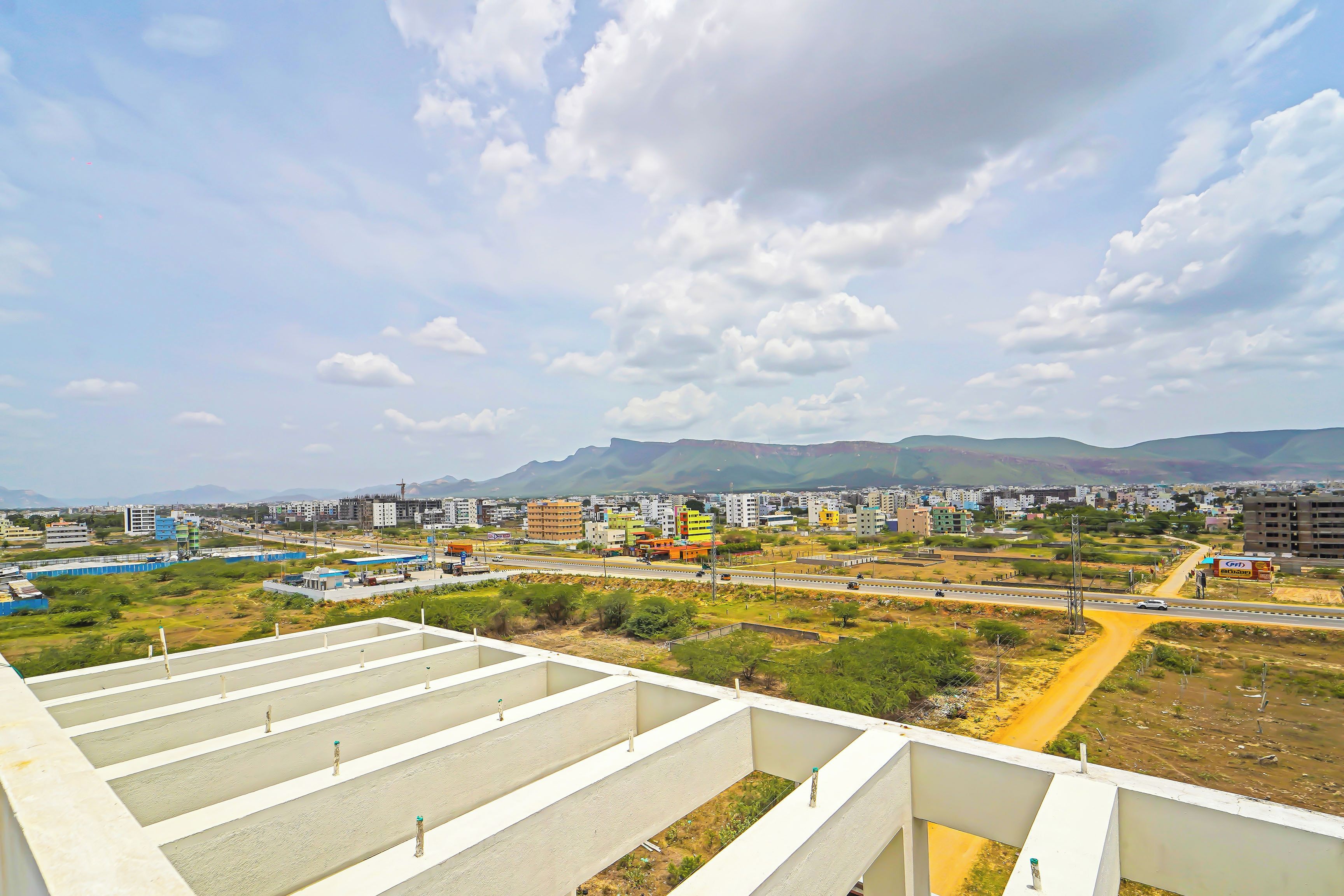 Un paisaje urbano con edificios, carreteras y una cadena montañosa distante.