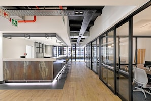 A modern office interior with a reception desk, bar stools, and glass walls. - Light-Filled Foreshore 1 Bed Gem with City Views with AC (Cape Town)