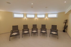 A waiting area with five chairs, a potted plant, and three windows. - Berghotel Rasis (Galtür)
