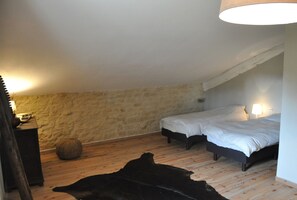 A bedroom with two beds, a stone wall, wooden flooring, and a hanging light fixture. - Holiday Home 'Numero 15' with Private Terrace, Private Garden and Wi-Fi (Autréville-Saint-Lambert)