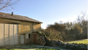 A stone building with a large wooden door and a smaller door, surrounded by a stone wall and vegetation. - Holiday Home 'Numero 15' with Private Terrace, Private Garden and Wi-Fi (Autréville-Saint-Lambert)