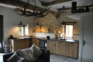 Una cucina moderna con parete in pietra, pensili in legno e illuminazione a sospensione.