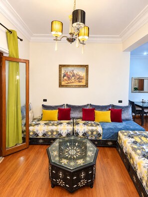A living room with a sofa set, a glass coffee table, and a painting on the wall. - 2-bedroom apartment in amazing Marrakech gueliz with cool AC and Pool (Marrakech)