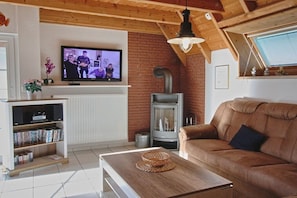 A living room with a television, a fireplace, a sofa, and a coffee table. - Sigrid's Beach Warden III (Wurster Nordseeküste)