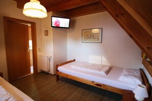A small, single-bed room with a wooden ceiling, a television mounted on the wall, and a framed picture above the bed. - Sigrid's Beach Warden III (Wurster Nordseeküste)
