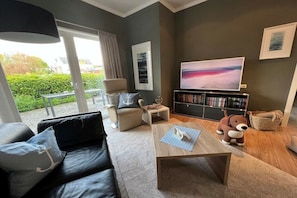 A modern living room with a sofa, coffee table, and a bookshelf. - Holiday home in Cuxhaven with swimming pool (Cuxhaven)