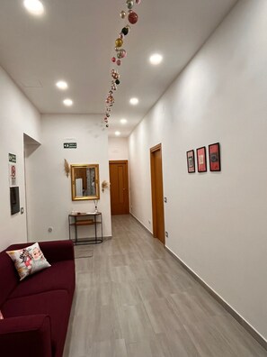 A hotel corridor with a reception desk, a wooden door, and framed pictures on the wall. - A relaxing vacation home surrounded by nature, just 5 minutes from downtown, with parking (Capezzano)