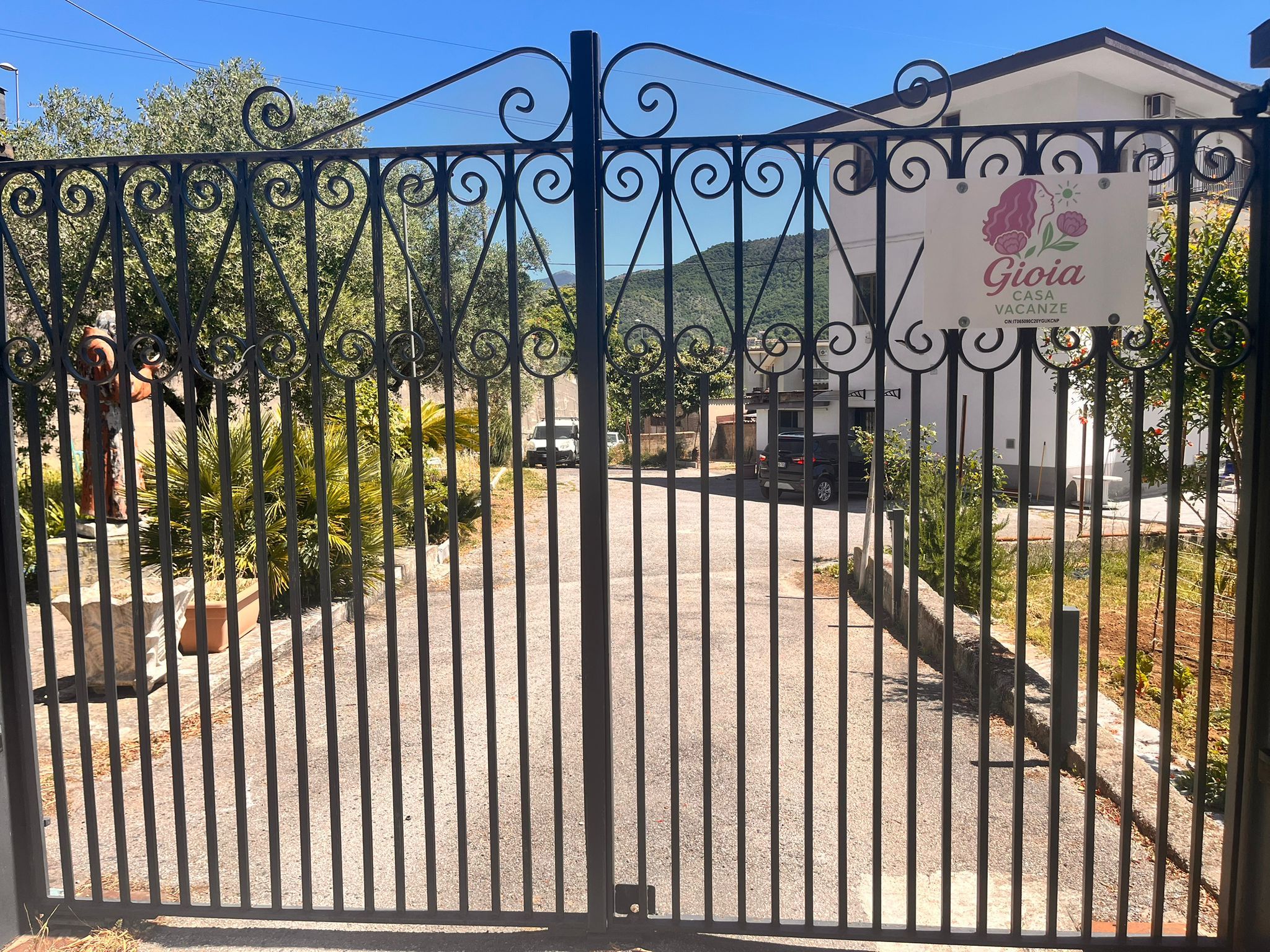 Une entrée fermée par un portail mène à une propriété sur laquelle est apposée une enseigne indiquant « Gioia Casa Vacanze ».