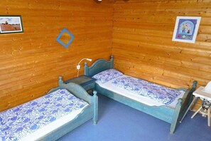 A small, cozy room with two beds, a desk, and a chair. - Log cabin at the Silver Lake (Frielendorf)