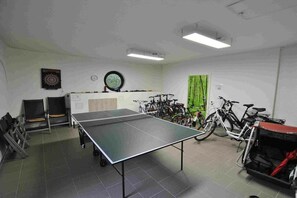 Ett rum med ett bordtennisbord, cyklar och träningsutrustning.