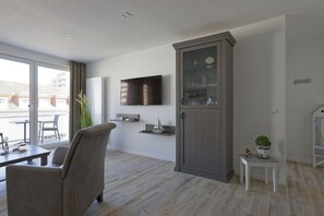 A modern living room with a sofa, a flat-screen TV, a cabinet with glass doors, and a small table with a plant. - Holiday apartment with 1 bedroom (Cuxhaven)