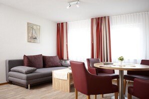 Ein modernes Wohnzimmer mit einer Couch, einem Esstisch mit Stühlen und einem Bild an der Wand.