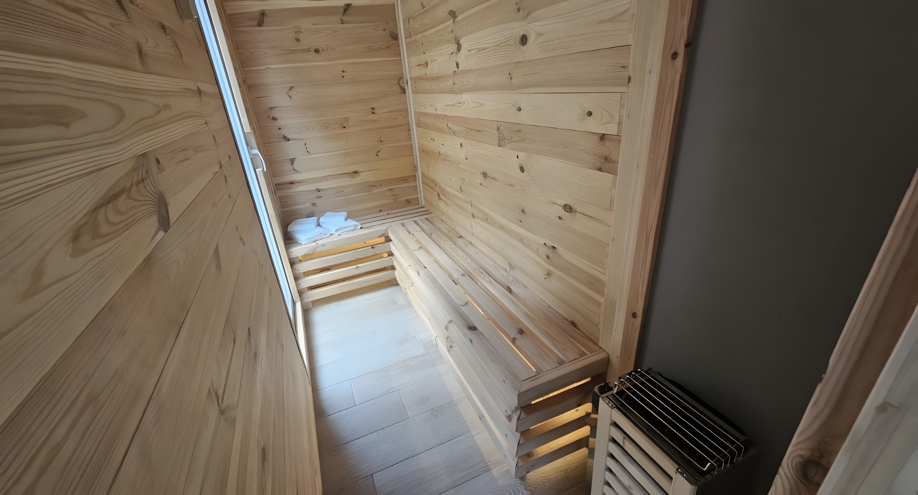 Een houten interieur met een schuine kap, een inbouwsbank en een ventilatie rooster.