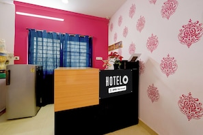 Zona de recepción de hotel con un mostrador de madera, una cortina azul y motivos decorativos en la pared.