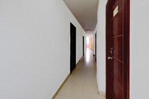 Un couloir bordé de portes des deux côtés, qui mène à une pièce lumineuse au bout.