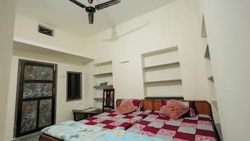 Un dormitorio con cama, ventilador de techo, ventana y estanterías empotradas.