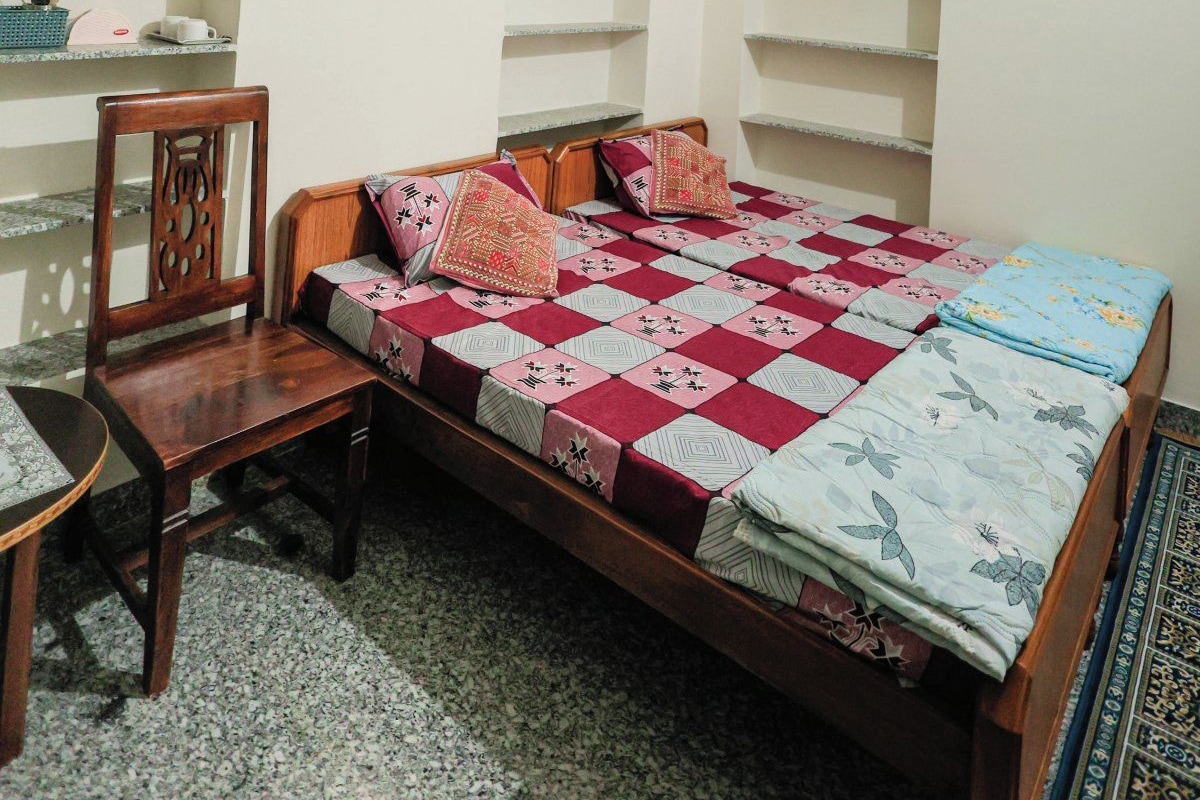 A bedroom with a bed, a chair, a ceiling fan, and built-in shelving.
