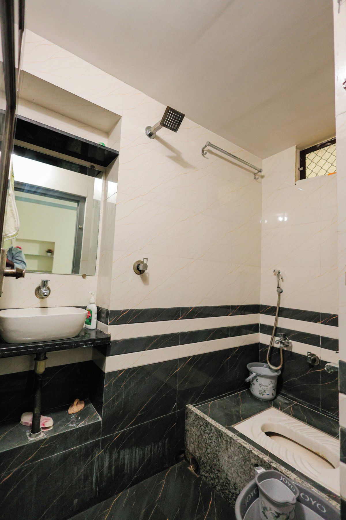 Baño con lavamanos, espejo, ducha e inodoro.