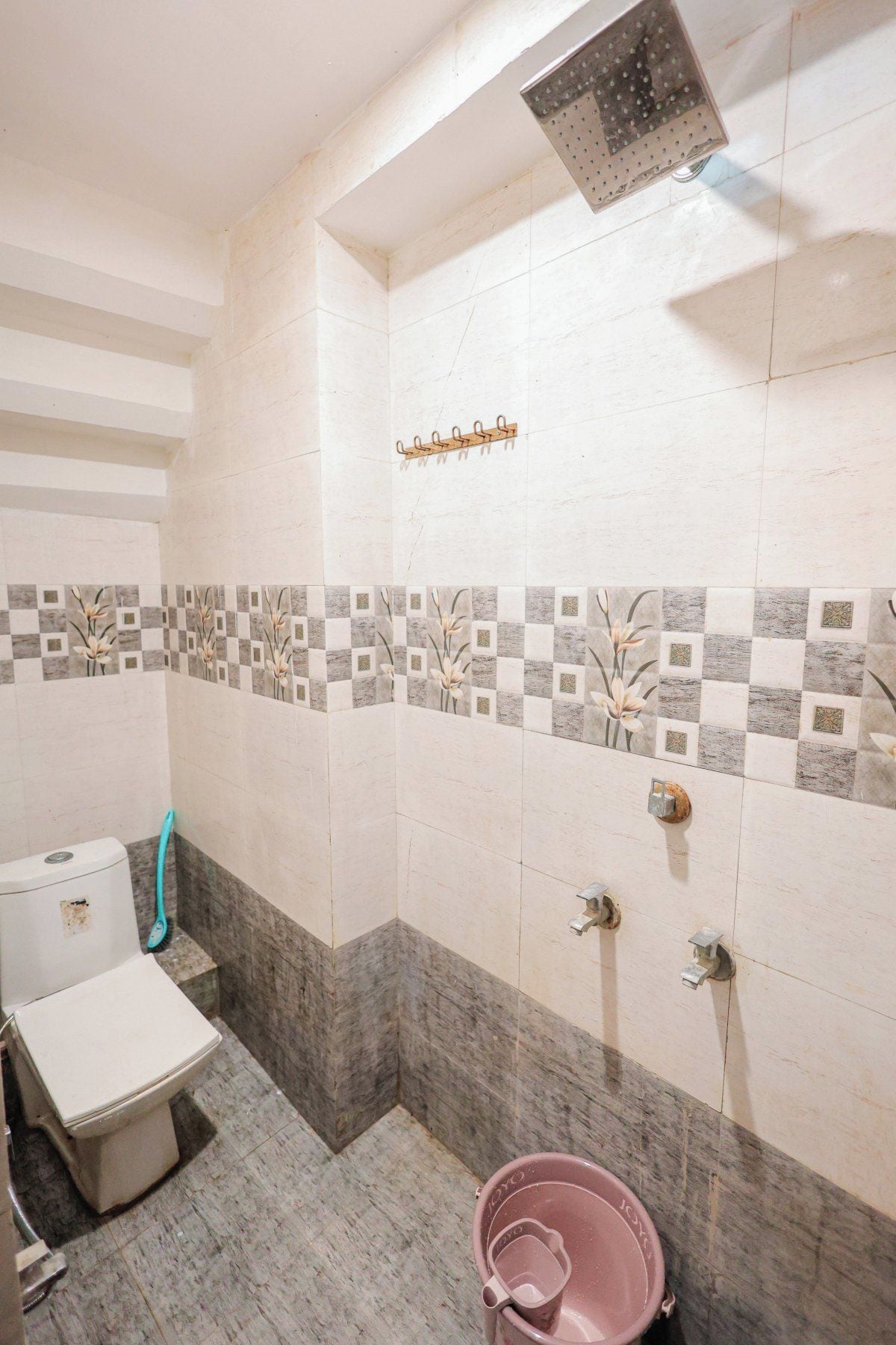 A bathroom with a toilet, shower, and a bucket.