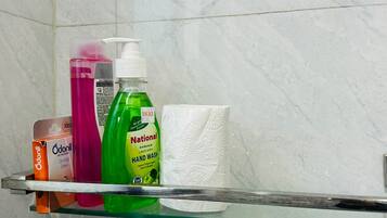 A bathroom shelf with various toiletries including a pink bottle, a green bottle, a white bottle, and a box.