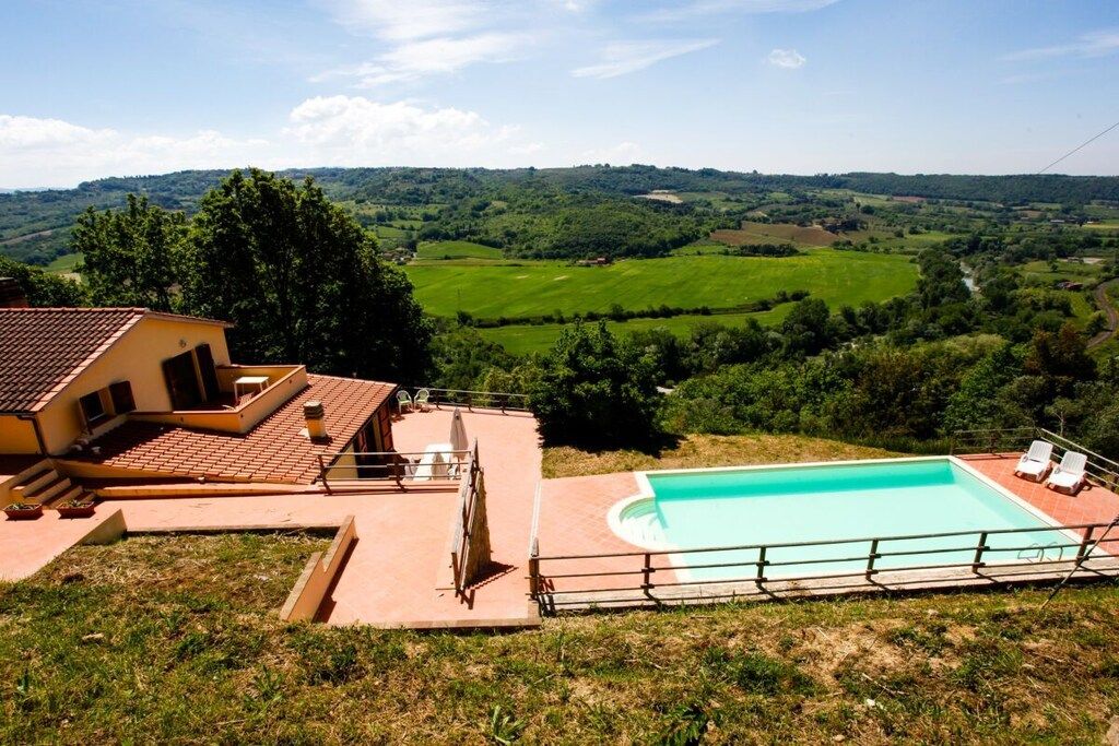 Ein Haus mit Swimmingpool, Terrasse und Blick auf eine grüne Landschaft.