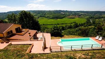 Ein Haus mit Swimmingpool, Terrasse und Blick auf eine grüne Landschaft.