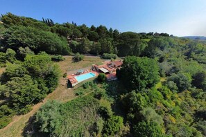 A property with a swimming pool, surrounded by dense greenery and hills. - Villa in Riparbella with swimming pool (Riparbella)