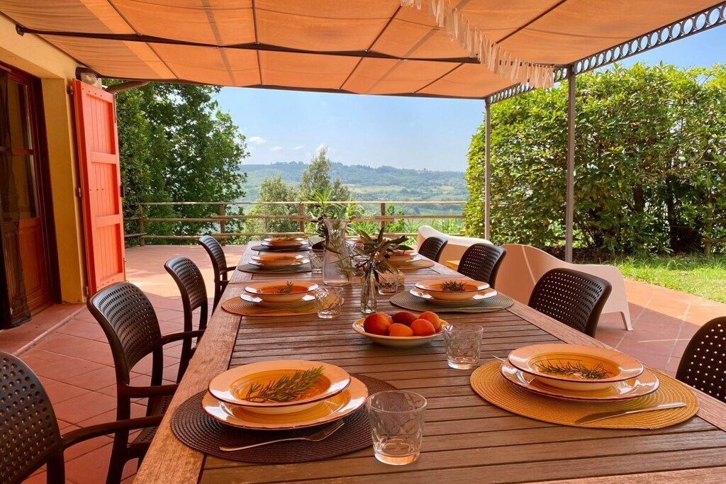 Ein Essbereich im Freien mit Blick auf die Landschaft, ein Tisch für vier Personen und Stühle mit gewebten Sitzkissen.