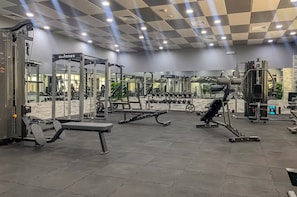 A gym with various exercise equipment, including weight machines and free weights. - Vogue | Marina Wharf Steps away to JBR Beach (Dubai)