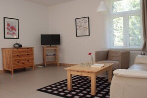Sala de estar com sofá, mesa de centro, televisão e cômoda.