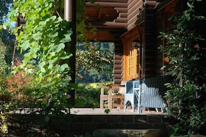 A log cabin with a covered porch, a stone wall, and a wooden bench. - Holiday home with 1 bedroom (Neuenkirchen)