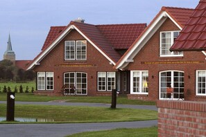 A brick building with a red-tiled roof, large windows, and a sign in a foreign language. - Sauna house in Wehldorf (Wurster Nordseeküste)